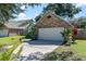 Attached two-car garage with brick accents, tropical landscaping and a concrete driveway at 692 Greenglen Ln, Palm Harbor, FL 34684