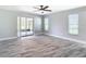 A spacious living room with gray floors, a fan, and a sliding glass door to the porch at 714 Lemonwood Dr, Oldsmar, FL 34677