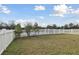 Large backyard enclosed by a white picket fence with a view of the tranquil pond at 7645 Windchase Way, Wesley Chapel, FL 33545