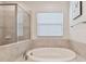 Soaking tub with tile surround and glass shower panel at 7645 Windchase Way, Wesley Chapel, FL 33545