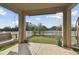 Covered patio featuring a hanging swing seat and a view of the fenced backyard and pond at 7645 Windchase Way, Wesley Chapel, FL 33545