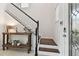 Bright staircase with dark wood treads and white risers adjacent to console table and decorative front door at 7645 Windchase Way, Wesley Chapel, FL 33545