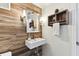 Chic half-bathroom featuring wood-look accent wall, vessel sink, and modern sconce lighting at 9012 Antigua Dr, Seminole, FL 33777