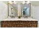 Bathroom featuring a double sink vanity with framed mirrors and a glass block shower at 9012 Antigua Dr, Seminole, FL 33777