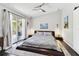 Bright main bedroom featuring dark wood floors, a ceiling fan, and balcony access with sliding glass doors at 9012 Antigua Dr, Seminole, FL 33777