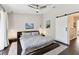 Bright main bedroom featuring dark wood floors, a ceiling fan, and a white barn door at 9012 Antigua Dr, Seminole, FL 33777