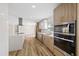 Bright kitchen featuring stainless appliances, white countertops, stylish range hood, and wood-look floors at 934 W Wheeler Rd, Brandon, FL 33510