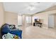 Spacious living room featuring tile floors, a ceiling fan, a large window, and a comfortable blue couch at 12112 Feldwood Creek Ln, Riverview, FL 33579