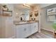 Bathroom featuring a double vanity with granite countertops, white cabinetry, and a large mirror reflecting natural light at 12818 Crested Iris Way, Riverview, FL 33579