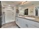 Bathroom with a double vanity with granite countertop, a walk-in shower with glass doors, and dark wood-look flooring at 12818 Crested Iris Way, Riverview, FL 33579