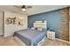 Comfortable bedroom featuring a blue accent wall, a ceiling fan, a bed with gray bedding, and an ensuite bathroom at 12818 Crested Iris Way, Riverview, FL 33579