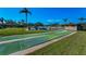 Outdoor bocce ball court surrounded by green grass and tropical palm trees on a sunny day at 2492 Laurelwood Dr # E, Clearwater, FL 33763