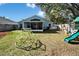 Large grassy backyard featuring a play set, mature trees, and fenced yard at 3902 Ixora Ct, Riverview, FL 33578