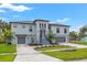 Gray two-story home featuring well-manicured landscaping, a two-car garage, and a inviting stairway to the main entrance at 58 Inness Dr, Tarpon Springs, FL 34689