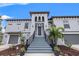 Inviting entrance of a two-story home featuring a stairway leading to the front door and lush tropical landscaping at 58 Inness Dr, Tarpon Springs, FL 34689