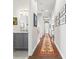 Long hallway with hardwood floors, neutral walls, and decorative rug leading to the home's powder room at 58 Inness Dr, Tarpon Springs, FL 34689