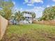 Expansive backyard showcasing a two-story home, grassy lawn, palm trees, and a wooden fence at 605 12Th N Ave, St Petersburg, FL 33701