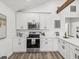 Modern white kitchen with stainless steel appliances, quartz counters, and wood-look flooring at 605 12Th N Ave, St Petersburg, FL 33701