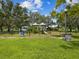 Fenced-in playground area features a variety of play structures surrounded by lush green grass and mature trees at 605 12Th N Ave, St Petersburg, FL 33701