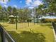 Large playground with swings and play structures on a cushioned surface, bordered by a fence and mature trees at 605 12Th N Ave, St Petersburg, FL 33701