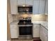 Close-up of the kitchen showcasing stainless steel appliances, white cabinets, brick backsplash, and granite countertops at 7044 Everest St, Spring Hill, FL 34606