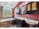 Bright bathroom featuring a soaking tub beneath a window and a vanity with dual sinks at 759 Timuquana Ln, Palm Harbor, FL 34683