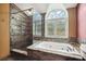 Bathroom featuring a shower with glass doors and a large soaking tub beneath an arched window at 759 Timuquana Ln, Palm Harbor, FL 34683