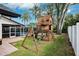 Outdoor fun awaits with this wooden playset, including swings and slide, adjacent to a screened pool at 759 Timuquana Ln, Palm Harbor, FL 34683