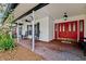 Inviting front porch featuring a brick floor, rocking chairs, ceiling fan, and a vibrant red door with glass panes at 759 Timuquana Ln, Palm Harbor, FL 34683