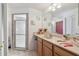 Bathroom with glass shower door, wood cabinets, and a big mirror at 9234 Duffer Ct, Hudson, FL 34667