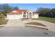 Charming single-story home featuring a three-car garage, light exterior paint, and red roof at 9234 Duffer Ct, Hudson, FL 34667