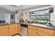 Sunlit kitchen with a sink by a window, light wood cabinets, and views of the outdoors, plus stainless dishwasher at 9234 Duffer Ct, Hudson, FL 34667