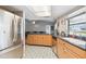 Open kitchen area with stainless steel refrigerator and a view into the Gathering room, natural wood cabinetry at 9234 Duffer Ct, Hudson, FL 34667