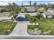 Aerial view of a blue single Gathering home with a brick driveway, lush landscaping, and palm trees at 114 12Th St, Belleair Beach, FL 33786