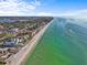 Stunning aerial view of the coastline featuring beachfront homes and clear turquoise waters under a bright blue sky at 114 12Th St, Belleair Beach, FL 33786