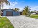 Charming single Gathering home featuring a patterned brick driveway, lush landscaping, and an attached garage at 114 12Th St, Belleair Beach, FL 33786