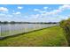 A serene backyard features a white fence, lush green grass, and a picturesque view of the lake at 11717 Navajo Sandstone St, Riverview, FL 33579