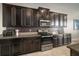 Kitchen featuring stainless steel appliances, dark cabinets, and tile backsplash at 11717 Navajo Sandstone St, Riverview, FL 33579