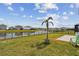 Scenic backyard features a grassy lawn, lakeside views, and a cozy fire pit, ideal for relaxation at 12326 Dora Trl, Parrish, FL 34219