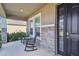 Cozy covered front porch with black rocking chairs and table at 12326 Dora Trl, Parrish, FL 34219