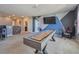 Spacious carpeted game room featuring a shuffleboard table, TV, and dartboard with unique geometric wall design at 12326 Dora Trl, Parrish, FL 34219