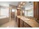 Bathroom featuring a double sink vanity, tub, and decorative glass block window at 1370 Pinellas Rd, Belleair, FL 33756