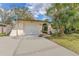 Front exterior with an attached one-car garage, arched entryway, and lush tropical landscaping at 13815 Capitol Dr, Tampa, FL 33613