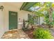 Inviting front porch with lush plants, tiled walkway and green door with decorative window at 13815 Capitol Dr, Tampa, FL 33613