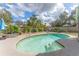 Backyard pool with a blue umbrella and chairs, surrounded by lush landscaping and fencing at 13815 Capitol Dr, Tampa, FL 33613