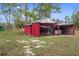 Rustic red outbuilding with open storage, ideal for lawn equipment and outdoor supplies at 14350 Hill Country Rd, Brooksville, FL 34614