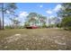 Extensive acreage showcasing a red outbuilding with a sprawling green landscape under a clear blue sky at 14350 Hill Country Rd, Brooksville, FL 34614