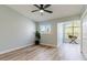 Bright room with wood-look floors, a ceiling fan, and plenty of natural light from large windows at 14700 Seminole Trl, Seminole, FL 33776