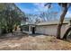 View of the home's backyard featuring mature trees, screened in porch and a rear entrance at 16106 Blackbeard Ln, Hudson, FL 34667