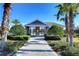 Community pool area with lush landscaping, gated entrance, and clear blue sky at 2112 Purple Orchid Pl, Ruskin, FL 33570